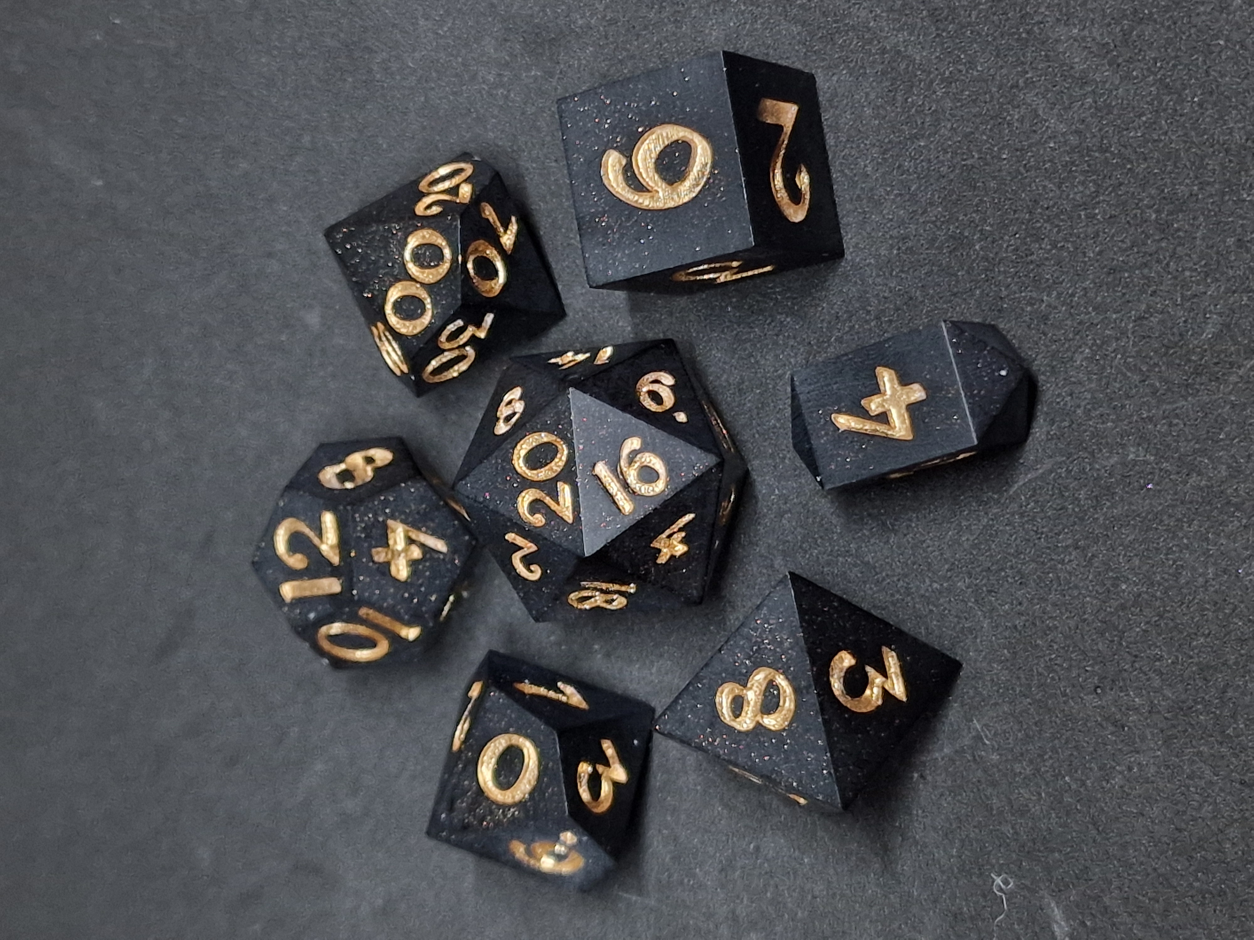 Fine sparks scatter across midnight-black dice, with golden numbers and crisp geometric faces.