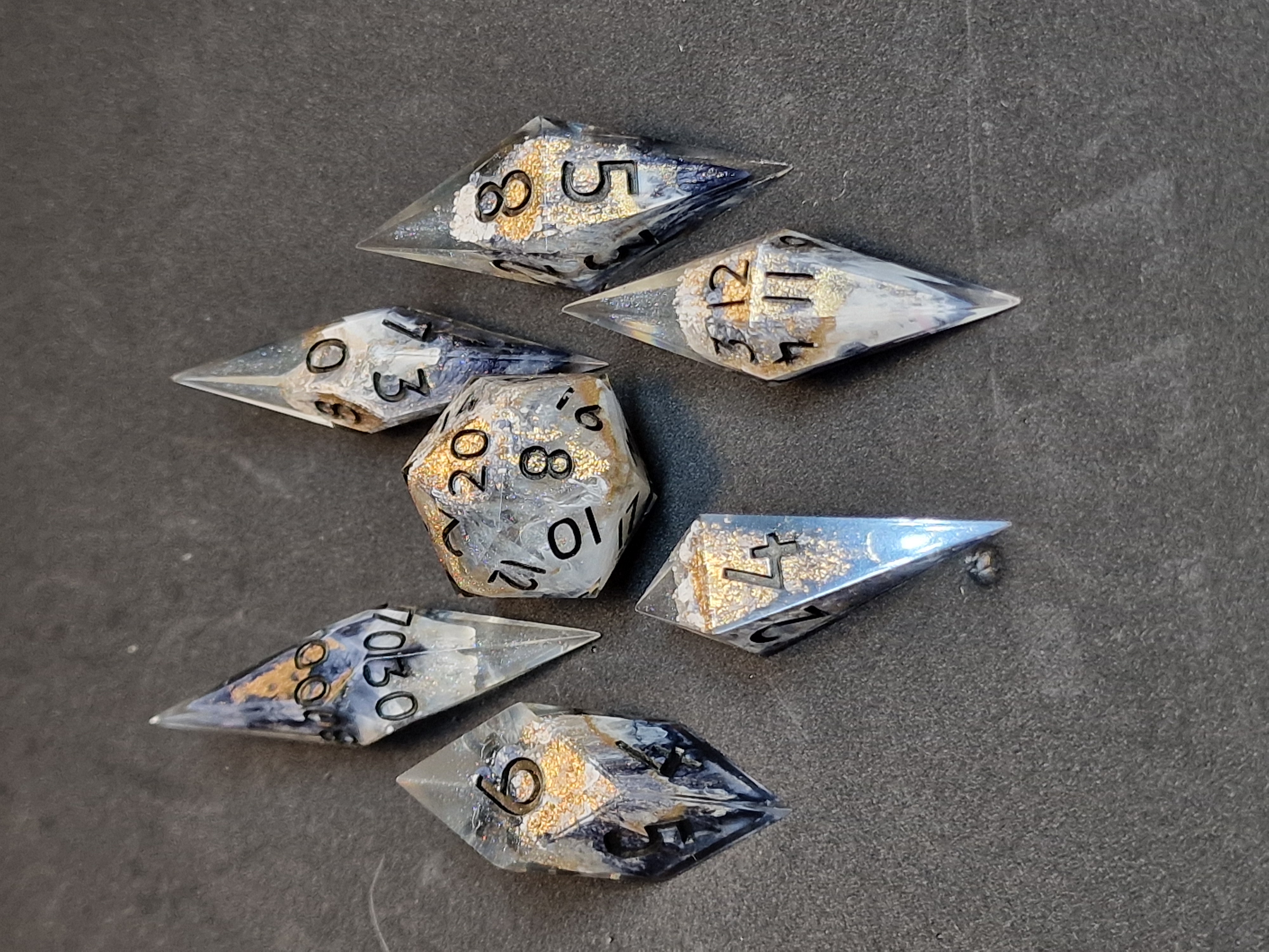 Inky blue and white wisps rise through clear shards, touched with antique gold and black numbers.